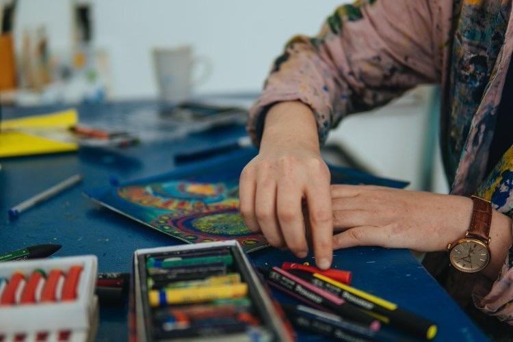 An artist's studio table with pastels, paints and brushes
